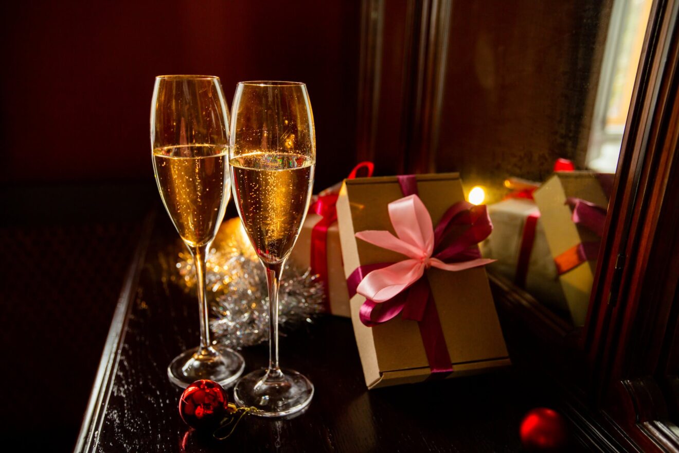 Composition of glasses of champagne placed on table near presents and festive decorations during Christmas celebration