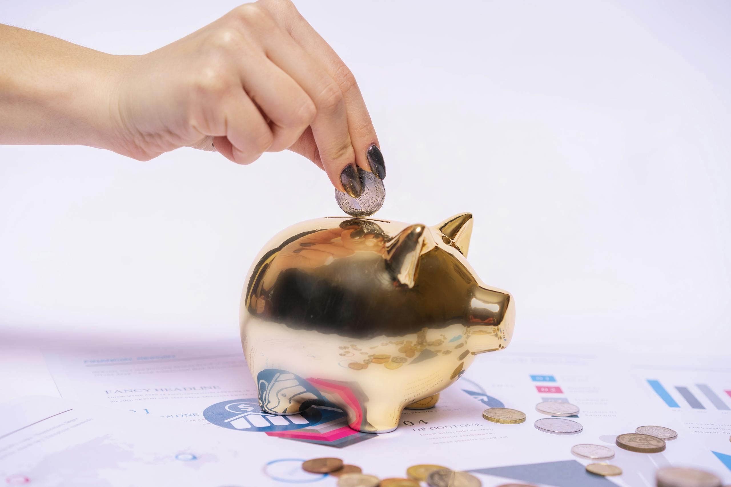 A hand places a coin into a golden piggy bank surrounded by financial documents, symbolizing savings.